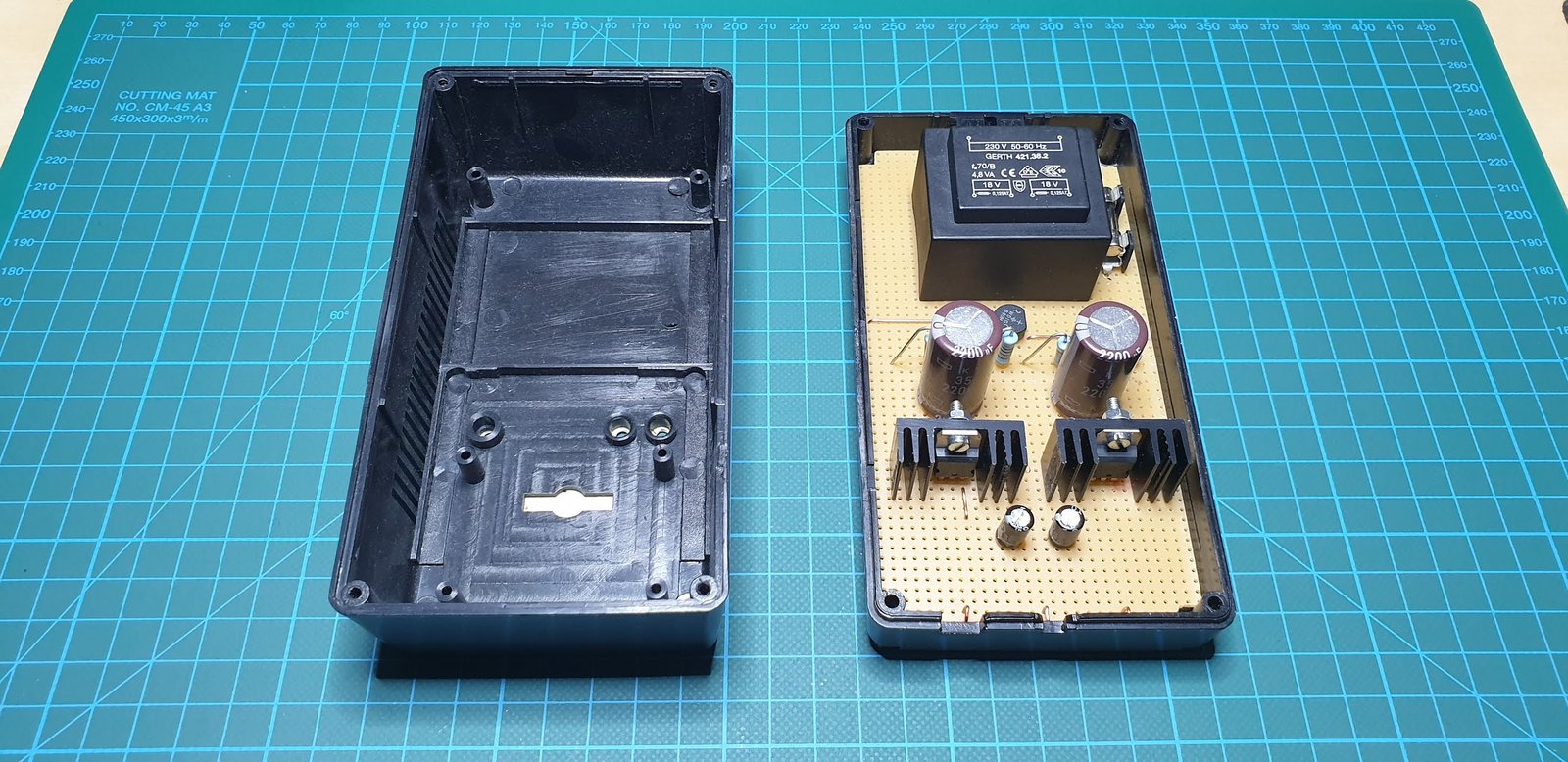 The power supply assembled on a prototyping board The power supply on a stripboard inside its box, next to the empty half of the box